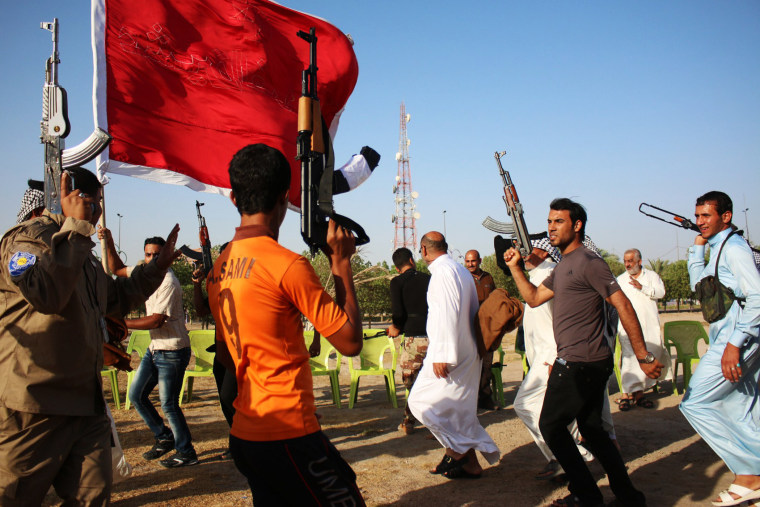 Iraqi Shiite fighters round dance raising up their weapons as they show their willingness to join Iraqi security forces in the fight against Jihadist militants on June 23, 2014 during a gathering in the southern city of Basra.