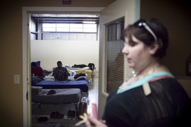 Residents at the Randy Sam's Outreach Shelter sit on their cots as Jennifer Laurent, right, the shelter's executive director, walks by, in Texarkana, Texas.