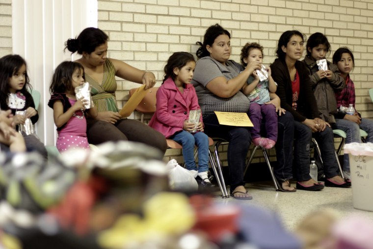 Migrants sit at the Sacred Heart Catholic Church temporary migrant shelter in McAllen, Texas