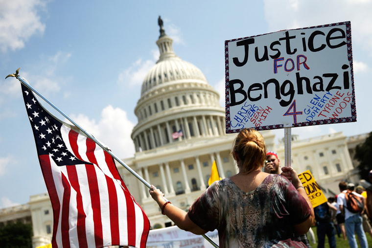 A woman holds signs during a \"Call to Action\" rally at the U.S. Capitol, marking the one year anniversary of the attacks on the U.S. compound in Benghazi, Sept. 11, 2013.