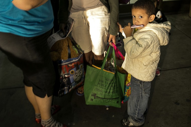 In this photo taken July 1, 2014, three-year-old Josefa, of Honduras, stands next to his mother, Eide Cerrato, center, as they prepare to board a bus leaving the city bus station in McAllen, Texas.