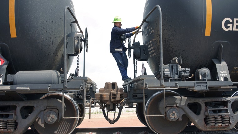 A worker climbs off a crude oil train after setting the handbrake at the Eighty-Eight Oil LLC's transloading facility in Ft. Laramie