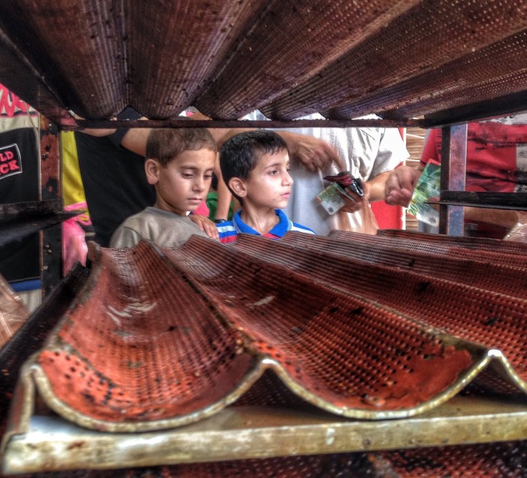 Two Palestinian boys stand in front of an empty bread rack at a Gaza City bakery, July 22, 2014, in Al Rimal, Gaza.