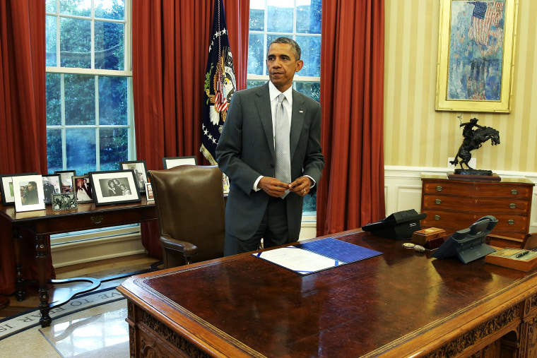 U.S. President Barack Obama stands at his desk in the Oval Office, August 4, 2014.