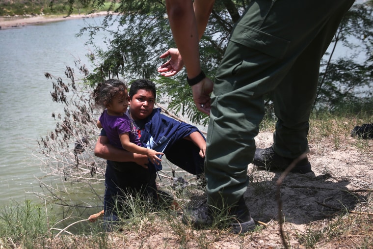 A U.S. Border Patrol agent assists undocumented minors after they crossed the Rio Grande from Mexico into the United States on July 24, 2014 in Mission, Texas.