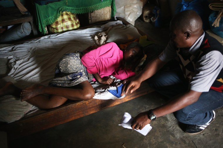 Community organizer John Saah Mbayoh speaks to a sick woman in her one-room home before she is taken to an Ebola isolation ward on August 15, 2014 in Monrovia, Liberia.