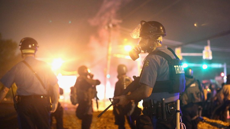 Police advance through a cloud of tear gas toward demonstrators protesting the killing of teenager Michael Brown on August 17, 2014 in Ferguson, Missouri.