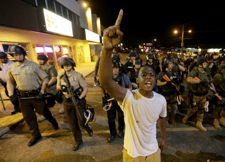 A man is moved by a line of police as authorities disperse a protest in Ferguson, Mo. early Wednesday, Aug. 20, 2014.