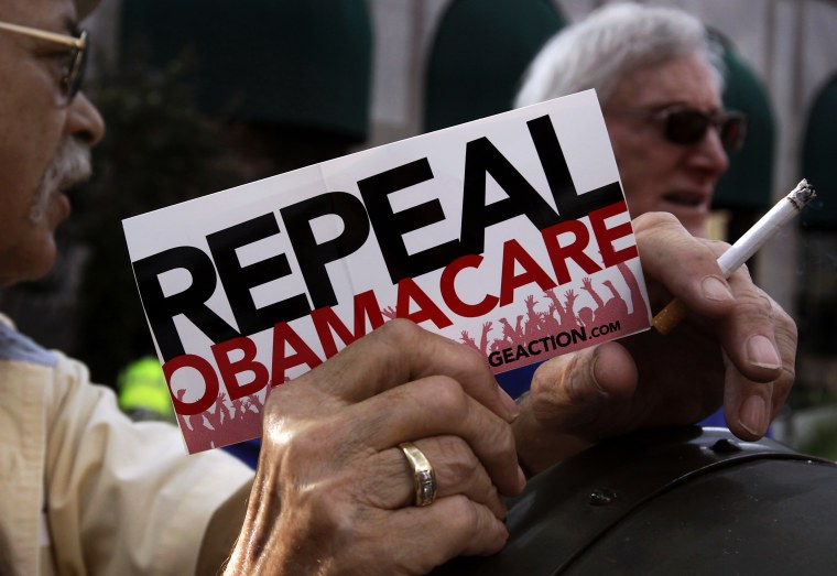 A small group demonstrates prior to former South Carolina Senator Jim DeMint's speech at a \"Defund Obamacare Tour\" rally in Indianapolis, August 26, 2013.