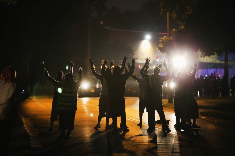 With their hands raised protesting the shooting of Michael Brown who was killed Aug. 9, residents gather at a police line as the neighborhood is locked down following skirmishes on Aug. 11, 2014 in Ferguson, Mo.
