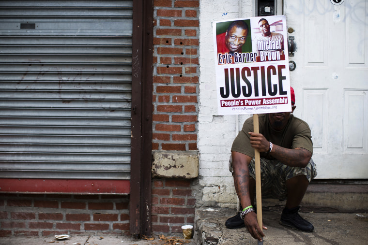 A demonstrator holds a sign bearing the likeness of Eric Garner and Michael Brown before a march to protest the death of Garner, Aug. 23, 2014, in the Staten Island borough of New York, N.Y