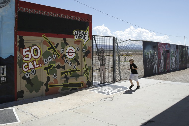 A young person runs by the Last Stop outdoor shooting range Wednesday, Aug. 27, 2014, in White Hills, Ariz. Gun range instructor Charles Vacca was accidentally killed Monday, Aug. 25, 2014 at the range by a 9-year-old with an Uzi submachine gun.