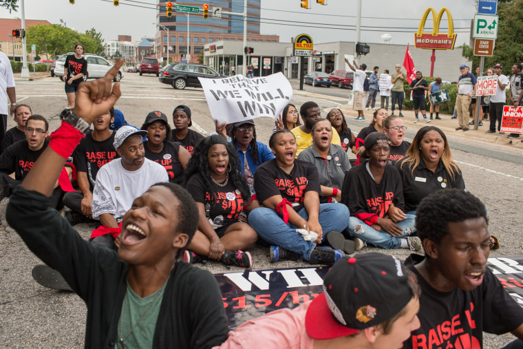 Fast food workers Darius Harris, foreground, Robert Martin, 18, and Vincent Whitehurst, 22, from Greensboro, N.C. sit in Morgan Street near Rigsbee Avenue in Durham, on Sept. 4, 2014 demanding that the fast food industry increase the minimum wage from $7.25 an hour to $15.