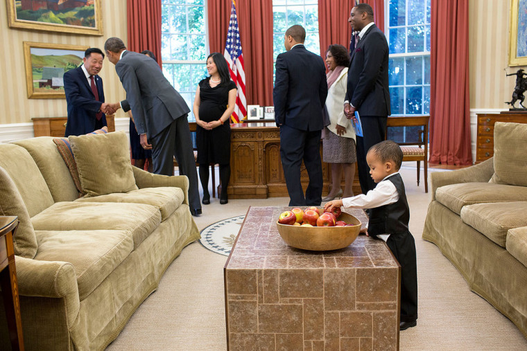 President Barack Obama greets the family of departing staff member Nik Smith, Confidential Assistant to the Administrator for Federal Procurement Policy, Office of Management and Budget, in the Oval Office, June 20, 2014. Smith's son reaches for an apple.