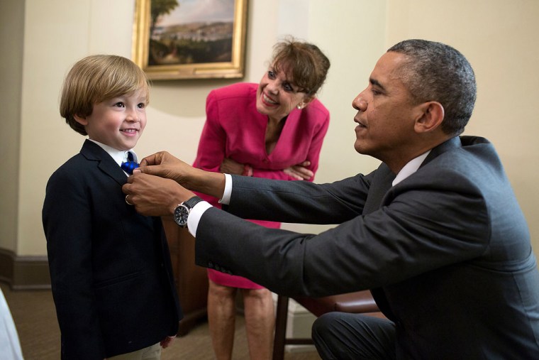 President Barack Obama adjusts the tie of Coast Guard Military Aide Cdr. Scott S. Phy's son outside the Oval Office, June 12, 2014. Cdr. Phy and his family were in the Oval Office for an award citation and departure photos with the President.