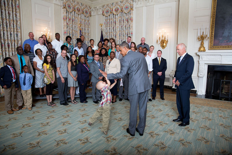President Barack Obama gives a little boy a high five as he and Vice President Joe Biden greet wounded warriors and their families during their tour in the East Room of the White House, June 23, 2014.