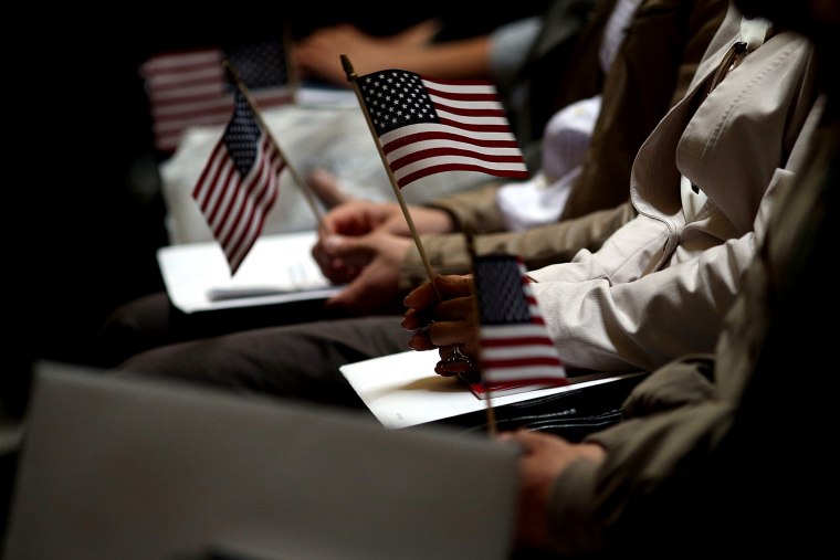People hold American Flags during a naturalization ceremony at Federal Hall for approximately 75 citizenship candidates from 31 countries on May 22, 2014 in New York City.