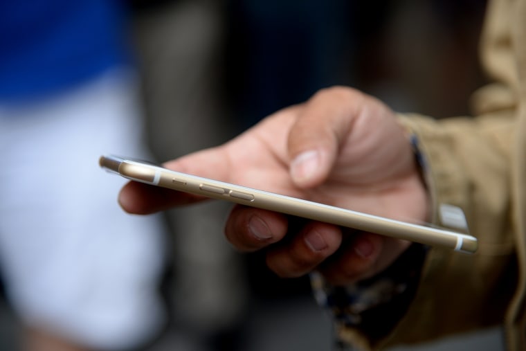 A customer checks out his new iPhone 6 Plus outside the Apple store in Pasadena, Calif. on the first day of sale, Sept. 19, 2014.