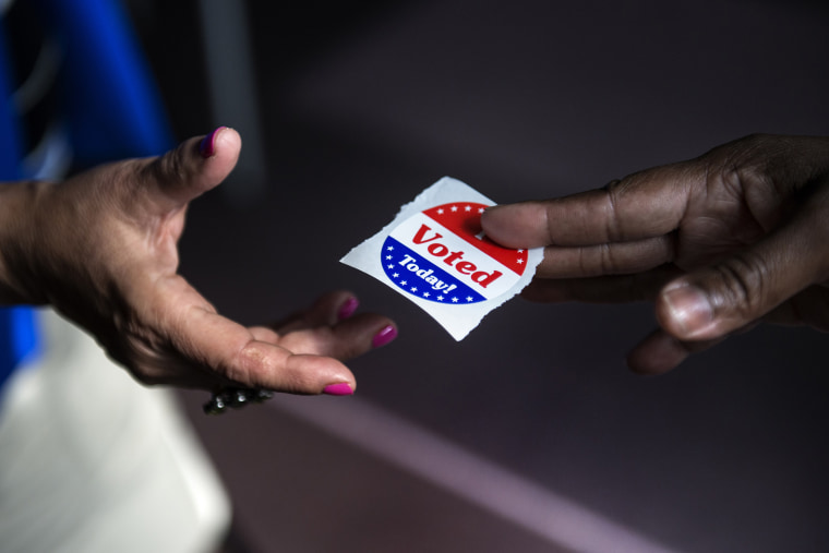 A poll worker hands out \"I Voted Today\" stickers on October 22, 2012.