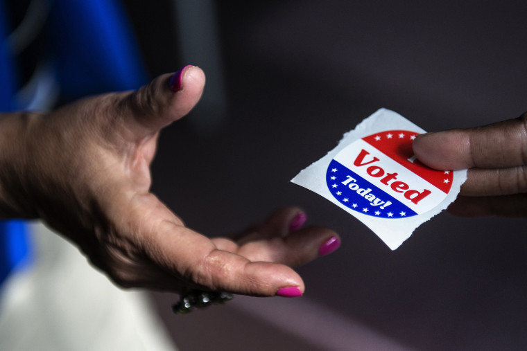 A poll worker hands out \"I Voted Today\" stickers on October 22, 2012