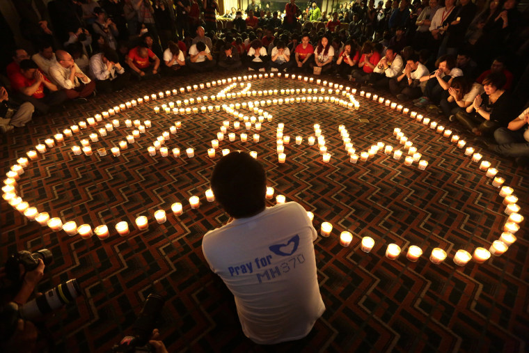 Relatives of passengers onboard Malaysia Airlines Flight MH370 pray during a candlelight vigil in the early morning, in Beijing on April 8, 2014. (Photo by Jason Lee/Reuters)