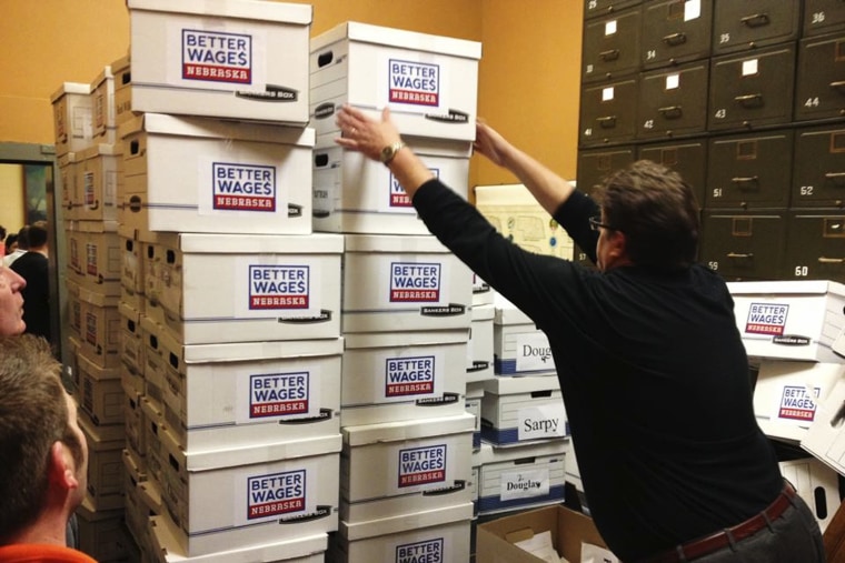 Deputy Secretary of State for elections handles boxes containing 134,899 petitions to raise the Nebraska minimum wage, enough to get the wage hike measure on the November ballot.