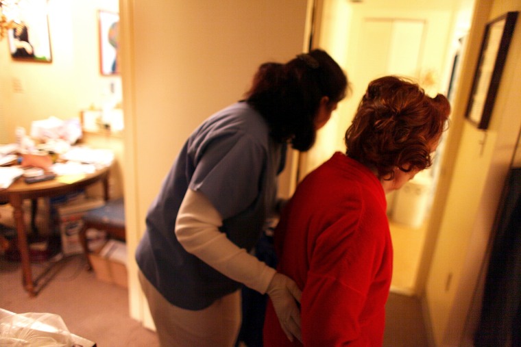 Home health aide Wendy Cerrato (L) helps a client in her apartment to bath and dress on January 6, 2010 in Miami, Fla.