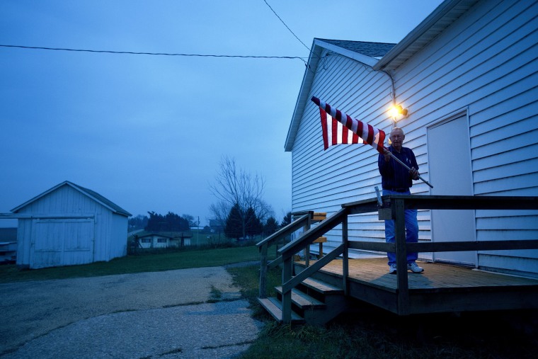 Election Inspector Jim Nodorft unfurls the American flag to hang it up outside the Smelser Town hall as the polls opened at 7 a.m. on November 6, 2012 in Georgetown, Wisconsin.
