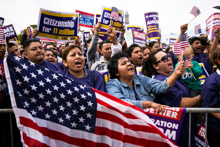 (L to R) Lorena Ramirez, of Arlington, Virginia, holds up an American flag as she cheers with her friend Lilia Beiec during a rally in support of immigration reform on October 8, 2013 in Washington, D.C. (Photo by Drew Angerer/Getty)
