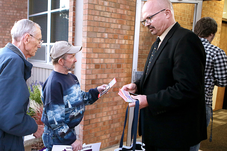 U.S. Senate candidate Dr. Doug Butzier, of Dubuque, right, hands out his campaign information in Davenport, Iowa on Oct. 11, 2014.
