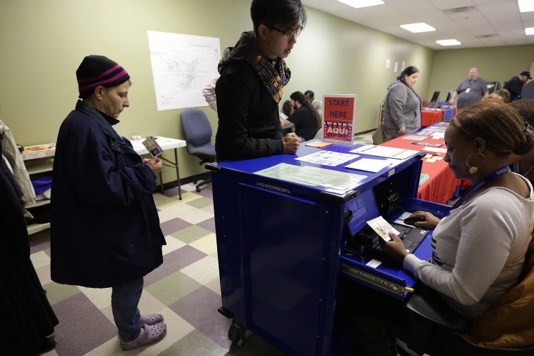 Voters stand in line to have an election official check their photo identification at an early voting polling site, in Austin, Texas on Feb. 25, 2014.