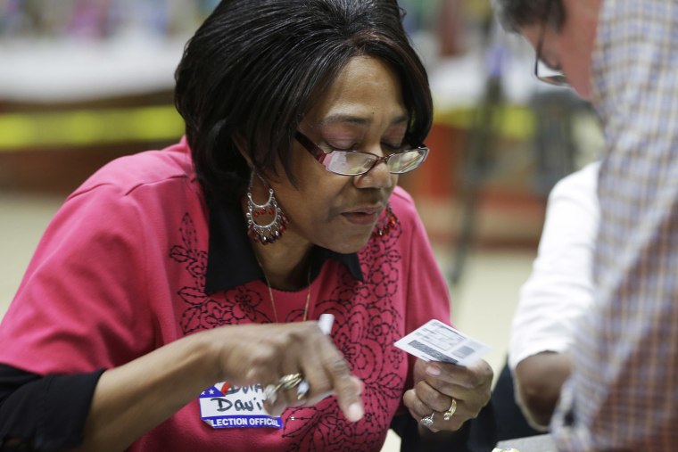 Election worker Dorothy Davis checks a voter's ID at a polling place in Little Rock, Ark. on May 20, 2014.