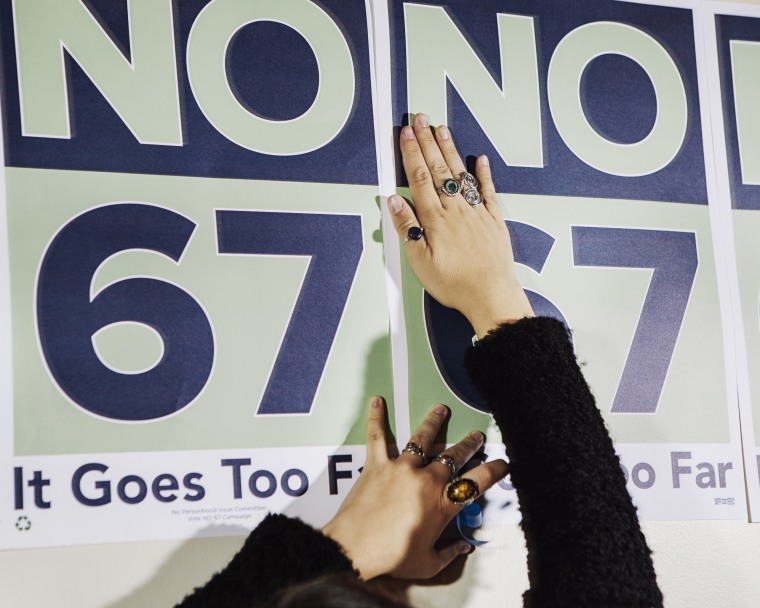 Elena Salisbury, 24, a Denver campaign organizer against Amendment 67, hangs signs before a press conference at Planned Parenthood.