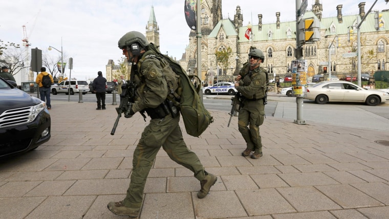 Armed RCMP officers head towards the Langevin Block on Parliament Hilll following a shooting incident in Ottawa on Oct. 22, 2014. (Chris Wattie/Reuters)