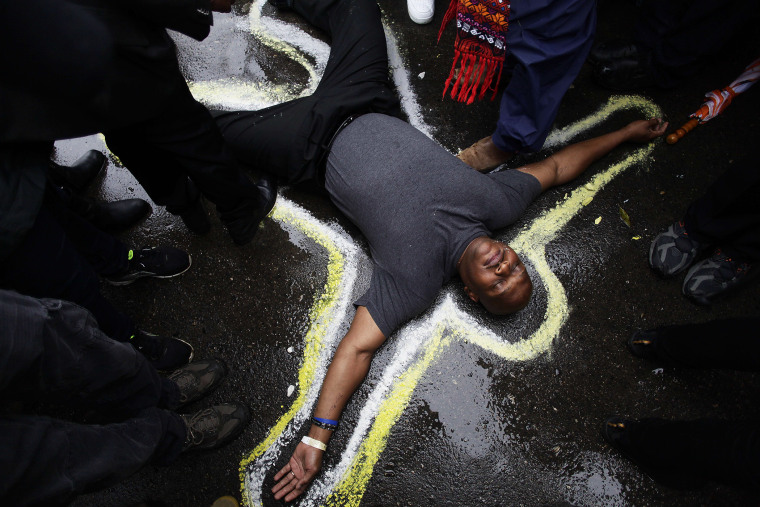 Pastor Charles Burton has his body outlined with chalk to replicate a crime scene as he and other demonstrators protest the shooting of Michael Brown outside the Ferguson Police Station on Oct. 13, 2014 in Ferguson, Mo.