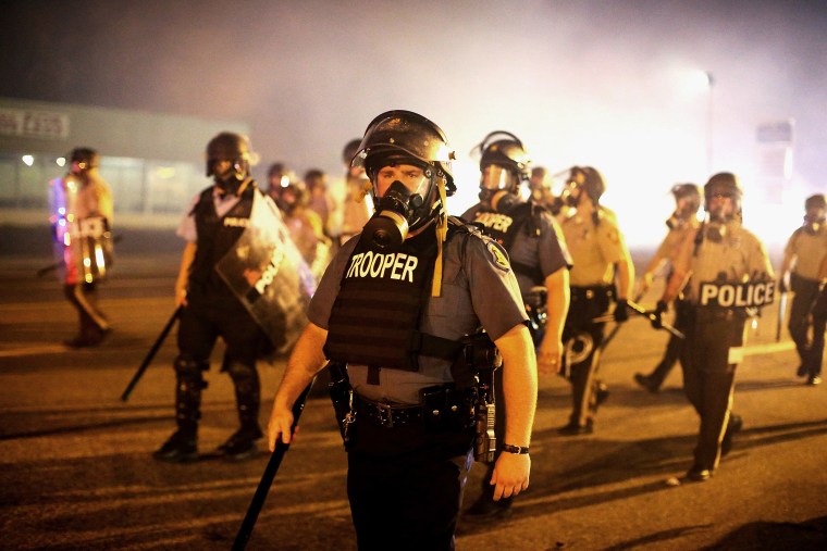 Police advance through a cloud of tear gas toward demonstrators protesting the killing of teenager Michael Brown on Aug. 17, 2014 in Ferguson, Mo.