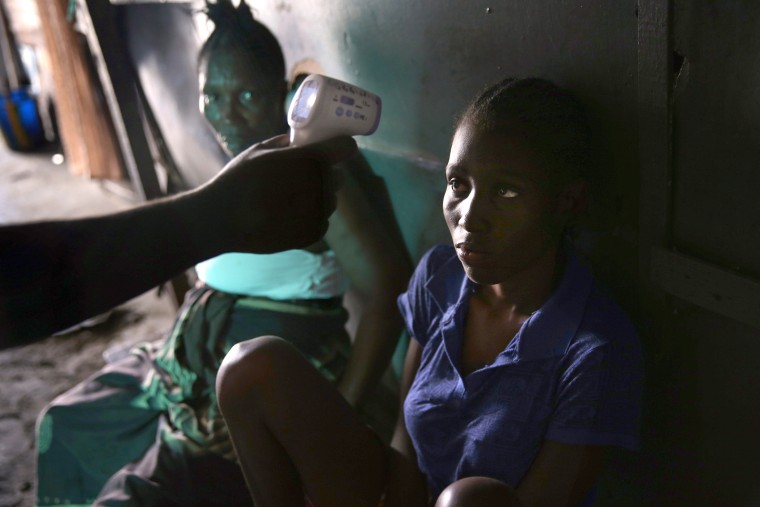 An Ebola tracing coordinator checks the temperature of Jessica Sompon, 17, finding her to have a fever in the West Point neighborhood on October 17, 2014 in Monrovia, Liberia.