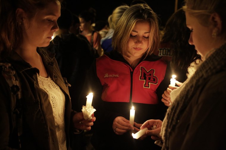 Katelynn Janisko (L-R), 15, Rachel Cowan, 15, and Jamison Strickland, 15, light candles at a vigil after a shooting at Marysville-Pilchuck High School in Marysville, Wash., Oct. 24, 2014. (Photo by Jason Redmond/Reuters)