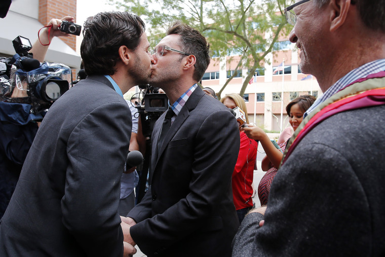 Kevin Patterson, left, and David Larance kiss after exchanging vows, as Rev. John Dorhaer, who performed the ceremony, stands at right, Oct. 17, 2014, in Phoenix, Ariz. (Photo by Rick Scuteri/AP)