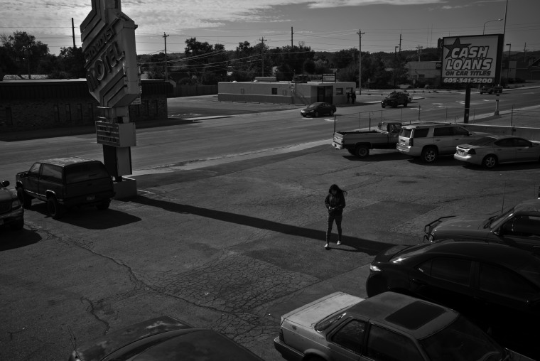 A woman walks through the parking lot of the Stardust Motel where many low income families live longterm, Rapid City, South Dakota. The street is lined with mostly dilapidated motels housing many people struggling to get by.