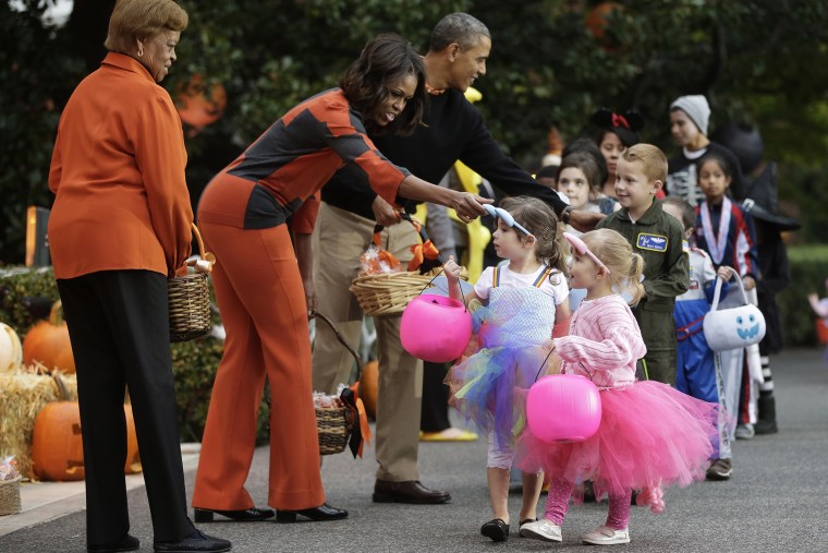 President Barack Obama, first lady Michelle Obama and her mother Marian Robinson, far left, hand out Halloween treats to 'trick-or-treaters' on the South Lawn of the White House in Washington, D.C., on Oct. 31, 2013. (Photo by Pablo Martinez Monsivais/AP)