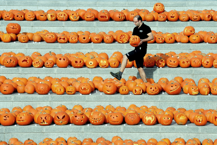 A worker carries a carved pumpkin amongst some of the 3000 pumpkins in Granary square nest to Regents canal in central London, England, Oct. 31, 2014.