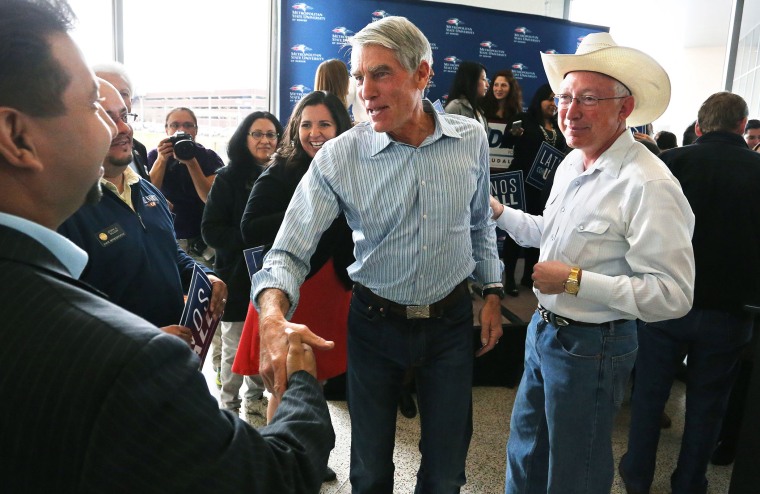 U.S. Sen. Mark Udall, center, flanked by former U.S. Secretary of the Interior Ken Salazar, right, greets supporters during a campaign stop focusing on Latino-American issues in Denver, Colo. on Nov. 3, 2014.