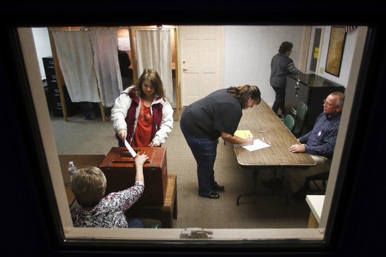 Voters cast their ballots and sign petitions at the polling place in town hall in Knox, Maine on Nov. 4, 2014.