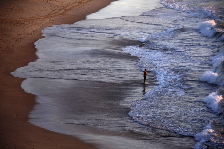 A lone swimmer prepares to enter the surf at sunrise on Sydney's Bondi Beach