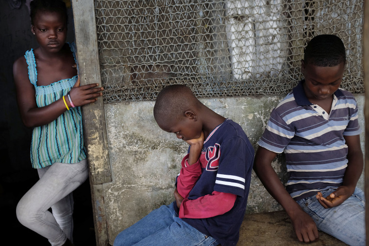 Promise, 16, Emmanuel Junior, 11, and Benson, 15, Cooper sit at their St. Paul Bridge home in Monrovia, Liberia on Sept. 28, 2014. (Jerome Delay/AP)