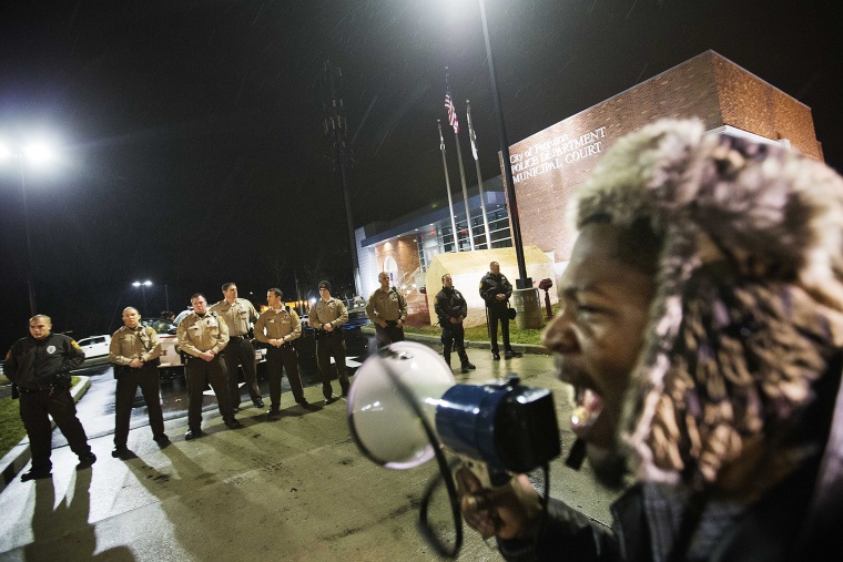 Protester Derrick Robinson shouts through a bullhorn at police officers standing guard during a demonstration outside the Ferguson Police Department on Nov. 23, 2014, in Ferguson, Mo. (David Goldman/AP)