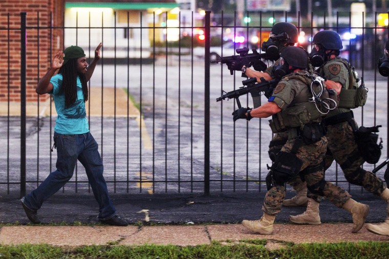 A man backs away as law enforcement officials close in on him and eventually detain him during protests over the death of Michael Brown, an unarmed black teenager killed by a police officer, in Ferguson, Mo., Aug. 11, 2014.