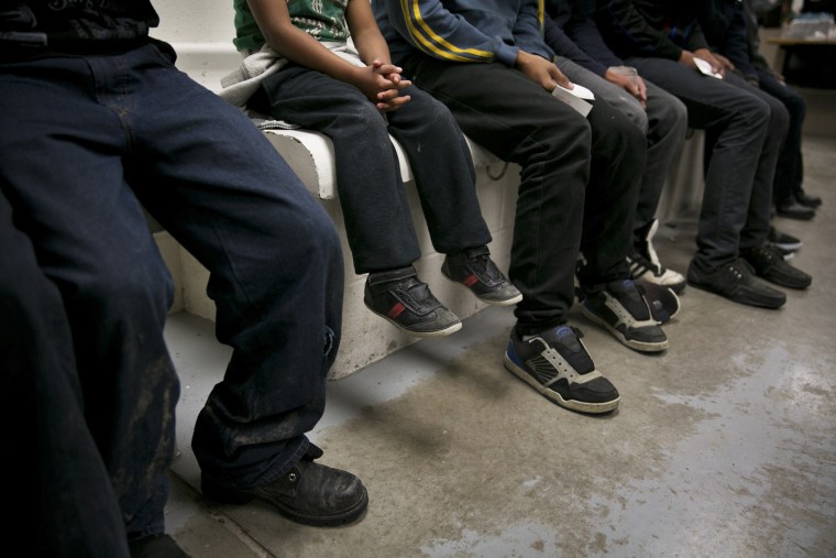 A child from Honduras sits with older youths being processed at a U.S. Border Patrol station in Brownsville, Texas, March 25, 2014. (Photo by Todd Heisler/The New York Times/Redux)