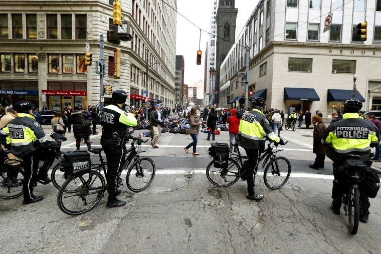Pittsburgh police on bicycles block traffic from demonstrators protesting the deaths of two unarmed black men at the hands of white police officers in New York City and Ferguson, Mo. as they lay in the street during march through Pittsburgh on Dec. 4, 201